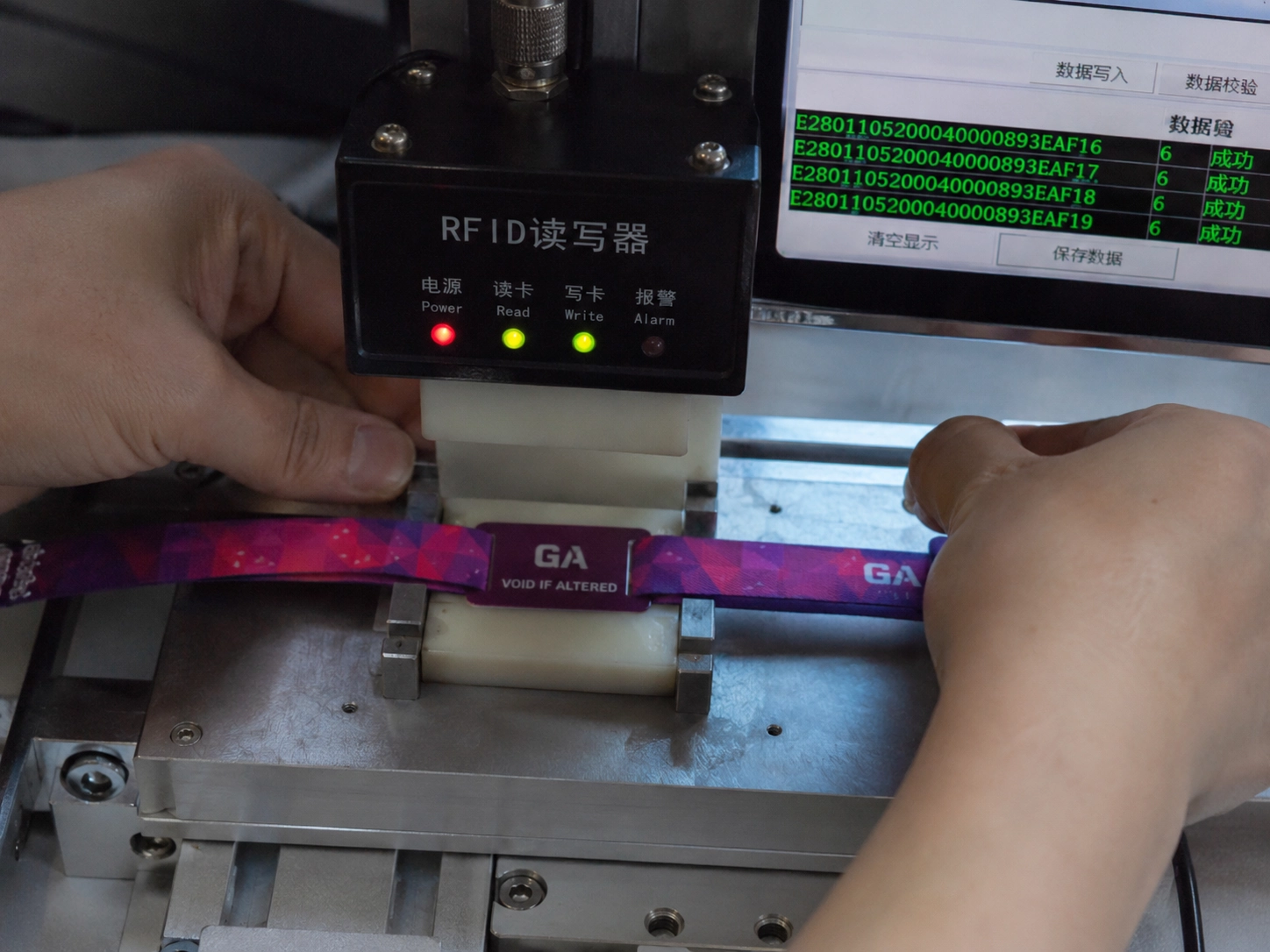 Technical close-up of RFID chip encoding and testing for festival wristbands